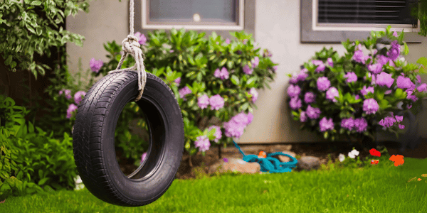 Neumático reciclado como columpio decorativo en un jardín, idea creativa y económica de mueble de jardín DIY para espacios con niños