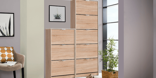 Mueble auxiliar tipo zapatero en acabado roble claro, con diseño vertical y cajones abatibles, ideal para mantener el orden en entradas o pasillos en una primera mudanza. Complementado con decoración moderna y plantas naturales, este mueble práctico y estilizado es parte esencial del checklist para quienes buscan funcionalidad y organización desde el primer día.