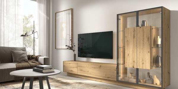 Salón moderno y funcional con mueble de TV bajo de madera clara, vitrina con iluminación interior y diseño contemporáneo, ideal para amueblar tu primer piso tras una mudanza. Acompañado de un sofá en tonos neutros, mesa de centro redonda y decoración minimalista, este espacio refleja lo esencial para crear un ambiente acogedor desde el primer día.