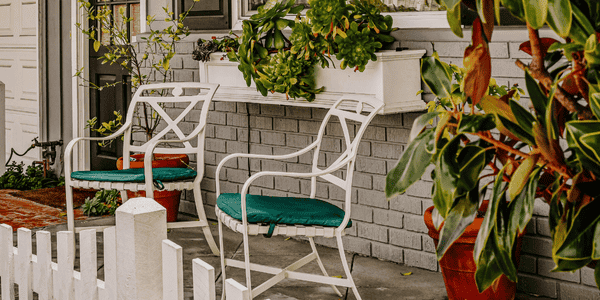 Terraza pequeña con estilo decorada con sillas blancas y cojines verdes, ideal para transformar balcones con bajo presupuesto y crear un rincón acogedor al aire libre.