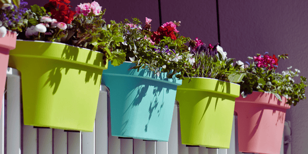 Accesorios baratos para terraza como maceteros colgantes de colores, perfectos para decorar balcón por menos de 100 euros y dar vida a espacios pequeños.