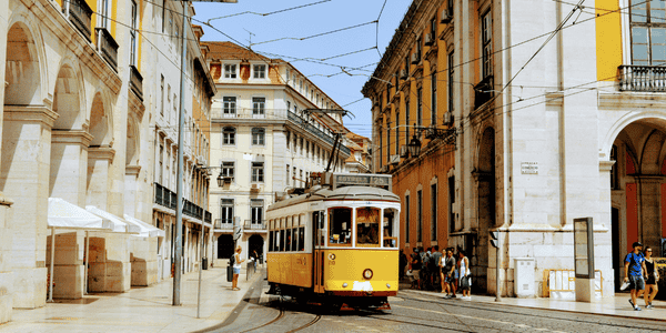 Se puede observar un tranvía en una calle estrecha y empedrada de Lisboa
