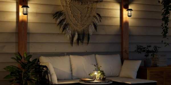 Terraza acogedora al atardecer con sofá de exterior blanco, decorado con luces de pared solares y un macramé, creando un ambiente cálido.